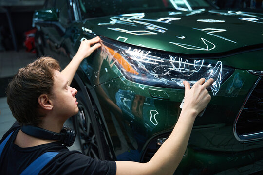 Experienced professional is applying protection film to auto headlight