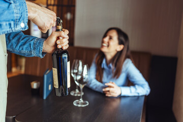Waiter Opening Wine Bottle for Smiling Woman at Restaurant Table During Casual Dinner Service