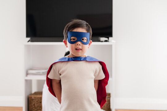 Asian boy standing in the living room wearing a superhero costume ready to play