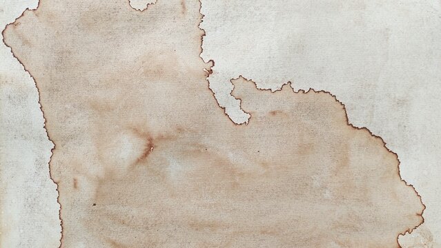 Coffee stain mark texture on white paper background. Dry brown coffee stain on textured paper surface.