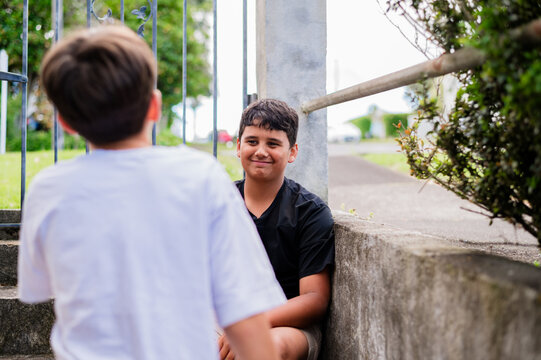 Two boys spending time outdoors near a concrete stairway bordered by a metal railing
