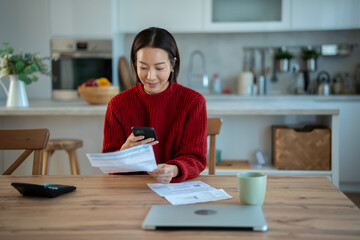 Woman managing home finances, paying bills using smartphone