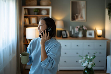 Woman talking on phone holding mug at home