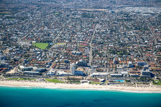 Aerial view of a beachside suburb with turquoise ocean, sandy beach and dense residential streets