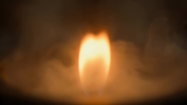 A bright, solitary flame with an orange-yellow core softly illuminates a dark, hazy void