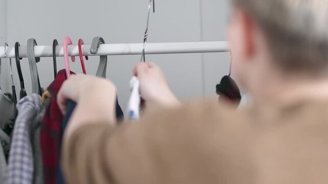 Hands cleaning and organizing messy closet with cotton shirts, 4K 10-bit.