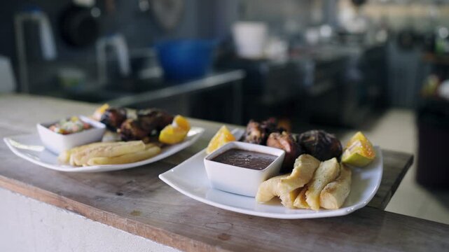 Two plates of delicious food with pork rinds, fried yuca, and sauce are ready to be served in a professional restaurant kitchen in Costa Rica