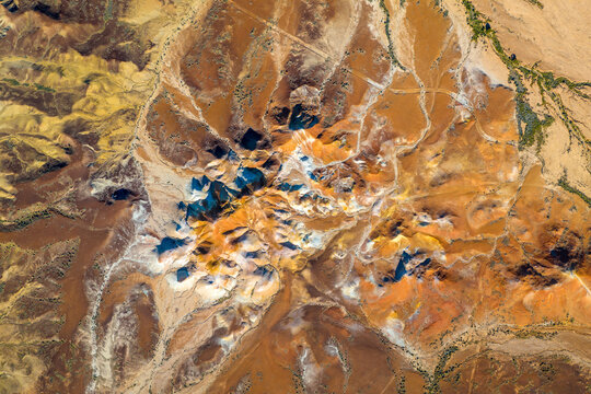 Overhead aerial view of a dramatic multicoloured outback mesa landscape with vivid ochre earth