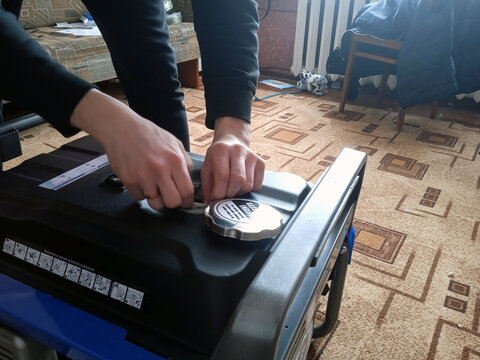 Person examines and adjusts the top of a generator in a home setting during the day