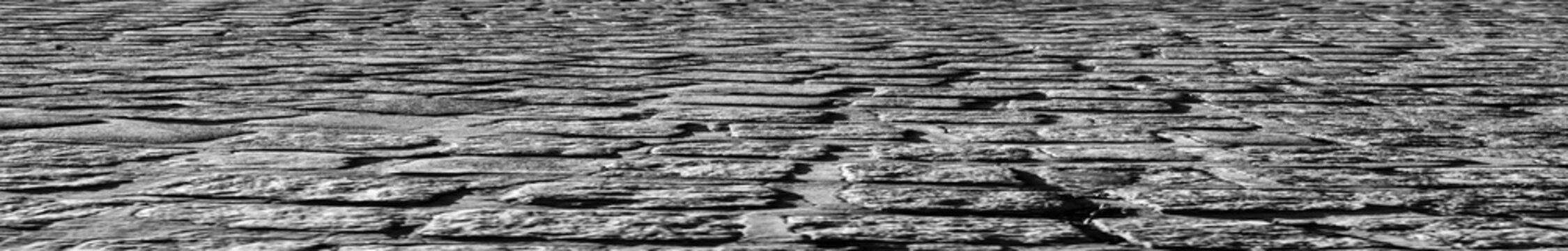 Old cobblestone road top aerial drone perspective view. retro aged cobble stone street pattern background. Cobblestone. Ancient rock floor texture top view. Sunny summer day Black and White colors