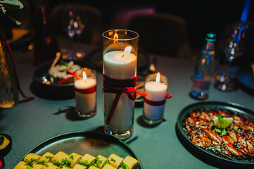 Photo of food, burning candle with a beautiful candlestick with a red ribbon at a banquet, a...