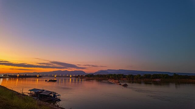 Time lapse Golden twilight illuminates the Fifth Thai&ndash;Lao Friendship Bridge as it spans the Mekong River, highlighting a new landmark of northeastern Thailand at dusk. Dreamy Skies at Sunset