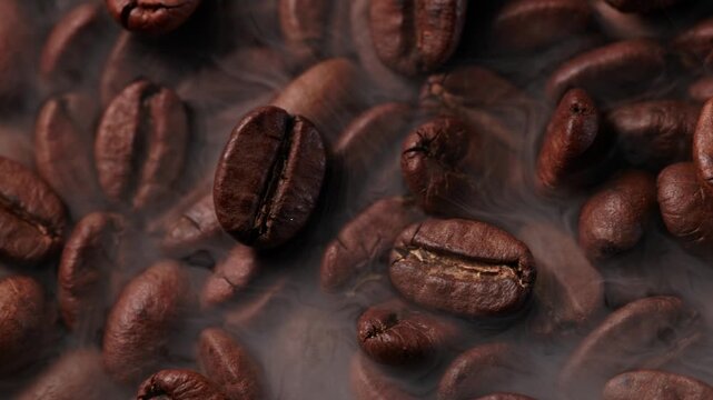 Macro process of roasting coffee beans with smoke on dark background, Slow sliding motion shot top view.