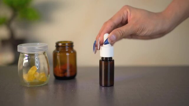 Hand-drip CBD oil from vials and vitamin capsules demonstrates holistic health on the white surface