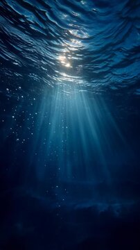 Underwater scene with sunlight rays penetrating deep blue ocean water.