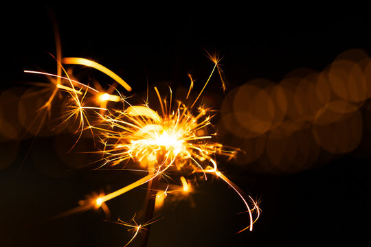 Sparkler glowing with sparks to celebrate new years eve with bokeh lights in background