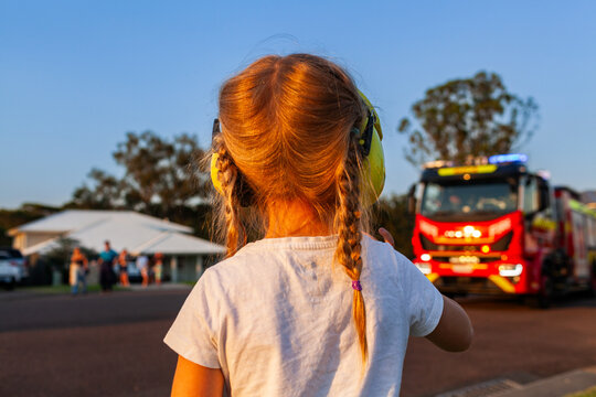 Little girl with earmuffs waving to santa on fire truck on lolly run at Christmas time