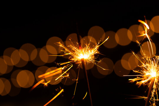 Sparkler glowing with sparks to celebrate new years eve with bokeh lights in background