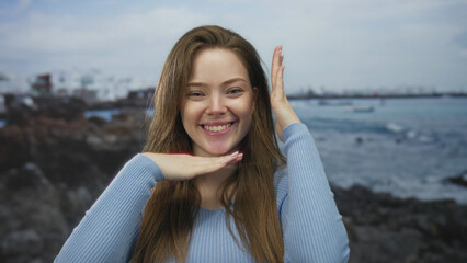 Young caucasian woman smiling and framing face with hands at sunny beach  playfulness joy creativity confidence. © Krakenimages.com