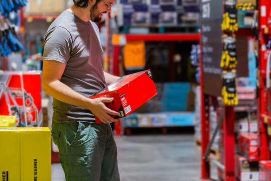 Man choosing product to purchase off shelf in hardware store shop