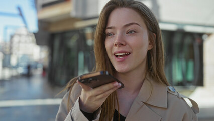 Woman holds smartphone to her mouth while speaking into it on a busy urban street, eyes focused ahead; connection.