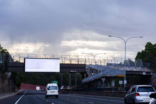 Van driving towards bridge overpass with digital billboard  above road
