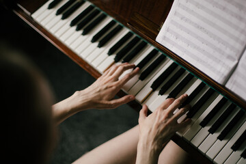 Fototapeta premium Beautiful young woman playing vintage piano in a cozy room.