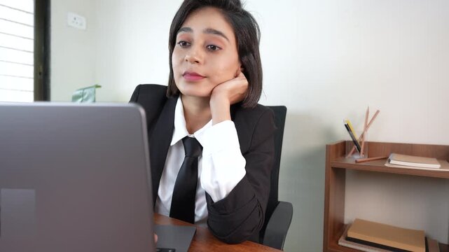 Close up of happy thoughtful young beautiful Asian businesswoman manager boss employee working on laptop, thinking creative ideas, sits on chair at workplace desk.
