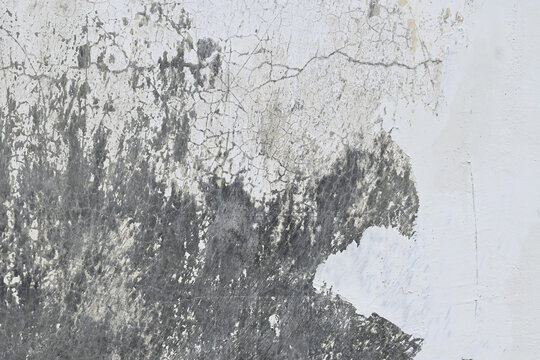 Weathered gray and white wall with cracks and peeling paint