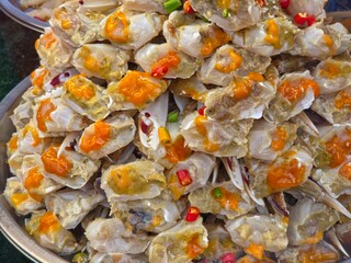 Pickled raw sea crabs with orange roe with fish sauce (Poo Kai Dong) on a large metal tray, capturing a popular and savory Thai street food delicacy known for its spicy and salty flavor profile. © Leiter1940s