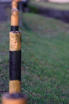 Weathered yellow and black bollards in a grassy area