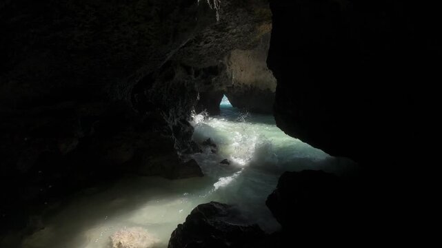 A beautiful slow motion shot of turquoise waves crashing in the caves at Suluban Beach in Uluwatu, Bali.  The sunshine bathes into the caves and rocks lighting up the dramatic huge crashing waves. I