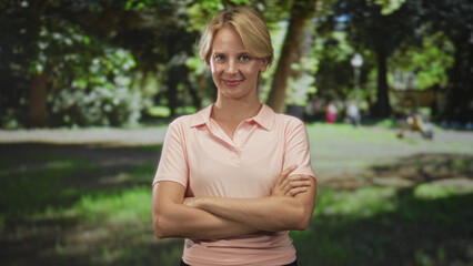 Woman with folded arms standing in forest wearing pink polo, eyes closed and slight smile, relaxed upright posture  serenity confidence. © Krakenimages.com