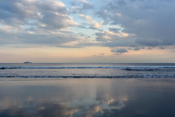 Obraz premium 夕方の空と夕焼けの雲を写している波打ち際と穏やかな水平線
