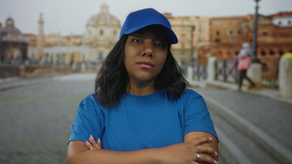 Woman in blue cap crosses arms in quiet historic stone square, head tilted forward by stone balustrade  rejection. © Krakenimages.com