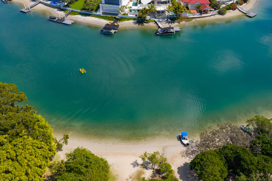 Aerial view of kayaks and small boats on a coastal canal lined with jetties and waterfront houses