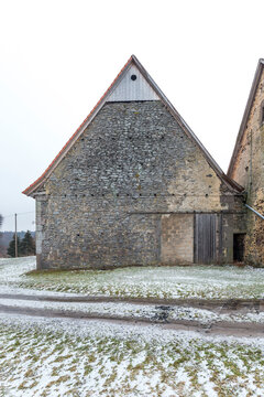 Giebelfassade einer Scheune im Vogelsberg vor einem verschneiten Feldweg