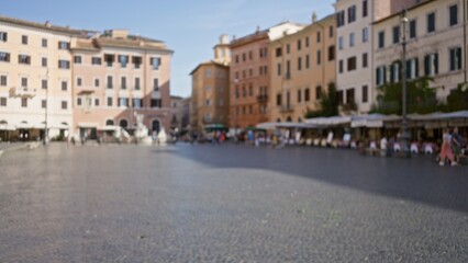 Obraz premium Defocused sunlit plaza scene with soft bokeh over cobblestone square and historic facades; backplate copyspace backdrop calm.