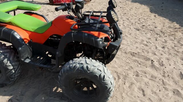 quad bike standing on coastal sand near sea under clear sky