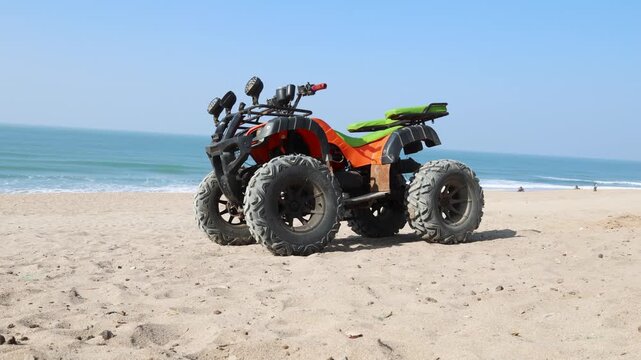 all terrain vehicle parked on sandy beach with ocean waves in background