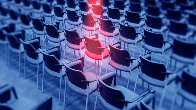 Leadership concept. Single red chair highlighted among rows of empty seats, symbolizing individuality, selection, recruitment or standout position in a group.