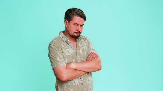 Middle-aged man looks away showing clear offense with slightly protruding lower lip furrowed eyebrows. Young adult guy isolated on blue background expressing emotional upset resentment dissatisfaction