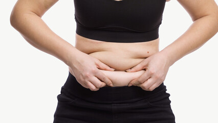 Close-up of plus-size woman touching stomach, highlighting weight loss results. Healthy lifestyle...