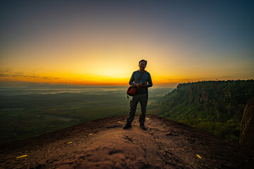 Naklejka premium Bueng Kan, Thailand. 02 December 2025; Three Whale Rock Iconic Viewpoint of Northeastern Thailand. Epic sunrise at a famous Thai viewpoint, capturing tiny human figures on a colossal rock ledge