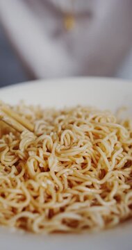 Medium shot of a hungry young man enjoying a delicious bowl of hot noodles
