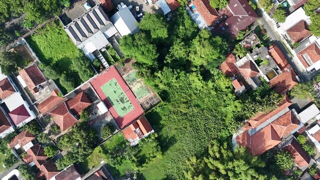 Top Down Aerial View of a Residential Neighborhood with a Tennis Court and Lush Greenery in Indonesia.