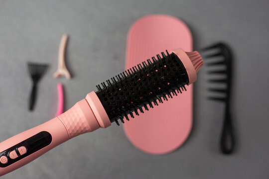 Professional pink electric hair styler set for beauty supply business. Complete kit with round brush, comb, mat, and clips in retail packaging. Perfect for small beauty shops and online stores