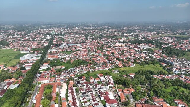 Wide Panoramic Aerial View of Dense Residential Area in Indonesia with Red Tile Roofs and Greenery.
