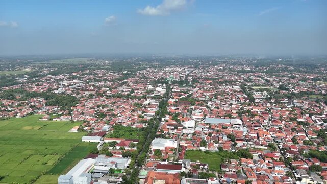 Wide Panoramic Aerial View of Dense Residential Area in Indonesia with Red Tile Roofs and Greenery.