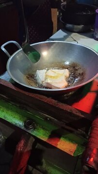 Tofu is fried to golden perfection before being mixed with traditional tahu tek tek seasoning, capturing a crispy texture and the authentic street food cooking process.